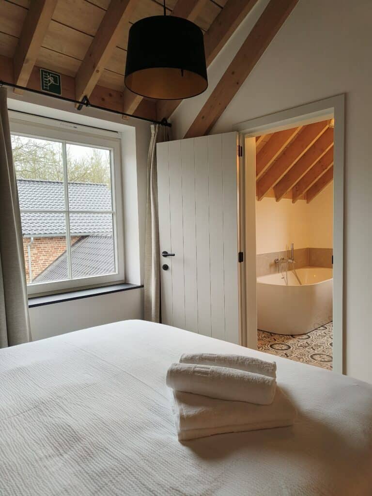 Slaapkamer met en-suite badkamer met bad in de vakantiewoning bij Hof van Sassenbroek in Tongeren-Borgloon, Haspengouw.