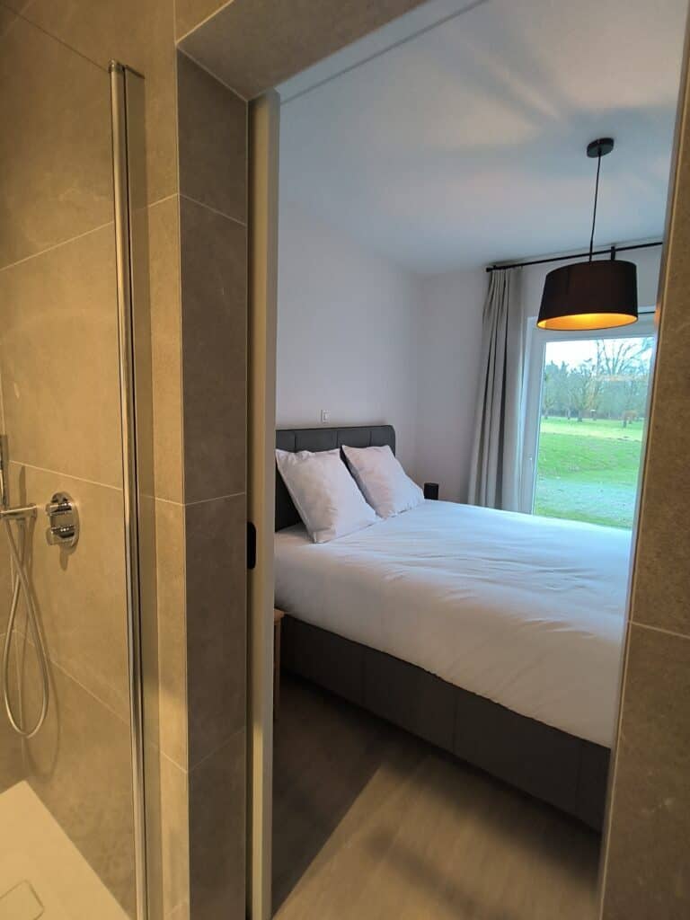 Slaapkamer met en‑suite badkamer en douche in het brouwhuis van de vakantiewoning bij Hof van Sassenbroek in Tongeren‑Borgloon, Haspengouw.