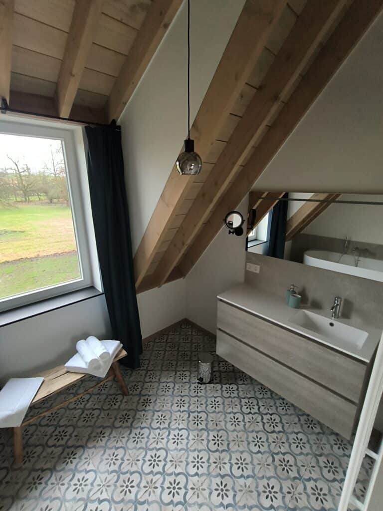 Lavabo in de en-suite badkamer met bad en uitzicht op de boomgaard van het brouwhuis van de vakantiewoning bij Hof van Sassenbroek in Tongeren-Borgloon