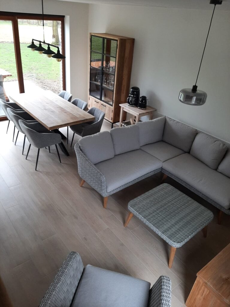 Zitgedeelte en eetgedeelte in de woonkamer van het brouwhuis met zicht op het terras en de hoogstamboomgaard van de vakantiewoning bij Hof van Sassenbroek in Tongeren-Borgloon, Haspengouw.